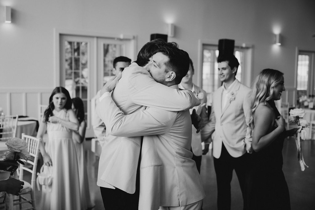 Groom and groomsman share an emotion filled embrace