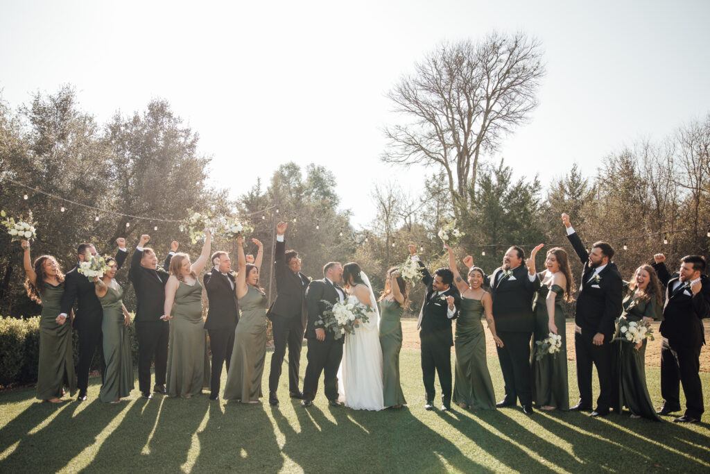 Wedding party cheers as bride and groom kiss